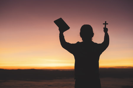 silhouette of a man Praying hands with faith in religion and belief in God On the morning sunrise background.  Prayer position.の写真素材