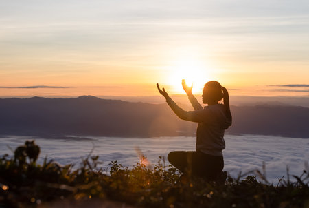 Silhouette of woman  praying over beautiful sunrise background, beautiful landscape, pay homage, spirituality and religion,man praying to god. Christianity concept.の写真素材