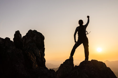 Silhouette of  A person standing on top of the mountain Travel and adventure. Mountain hiking. Mountains during sunrise. Success and goal achievement. People success.の写真素材