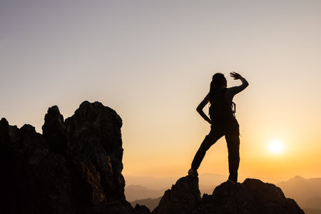 Silhouette of  A person standing on top of the mountain Travel and adventure. Mountain hiking. Mountains during sunrise. Success and goal achievement. People success.の写真素材