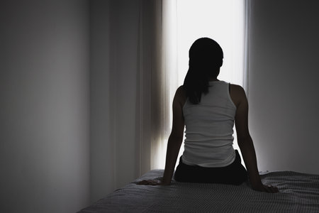 Silhouette of Young women sitting in dark room feeling pain with life problem. suffering from husband violence, domestic violence.の写真素材