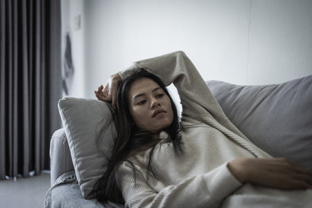 Tired, headache and stress of woman in living room with mental health, fatigue and sad problem. Face, depression and frustrated male person with anxiety, brain fog or crisis of failure.の写真素材
