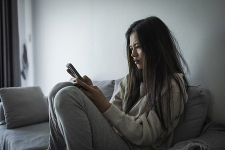 Young Asian woman sitting  on the sofa at home, feeling sad tired and worried suffering depression in mental health. in concept of depression anxiety and insomniaの写真素材