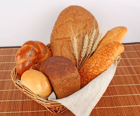Composition of fresh bread and bakery in basket with ear of wheat, foodstuffsの写真素材