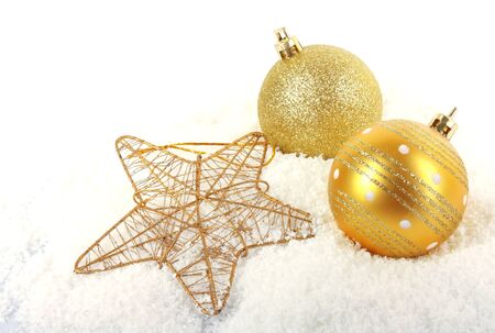 Christmas golden baubles with star on snow background, New Year holiday photoの写真素材