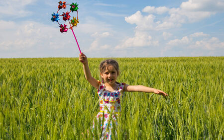 Cute little girl in green wheat field against skyの写真素材