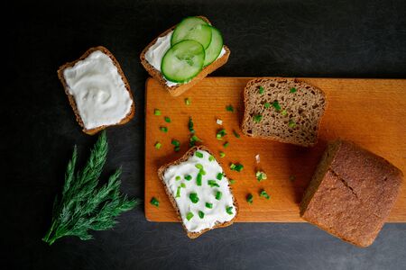 Open sandwiches with bread, cream cheese and cucumbers, food photo on wooden