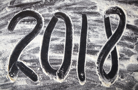 2018 New Year written in flour on black wooden background, food photoの写真素材