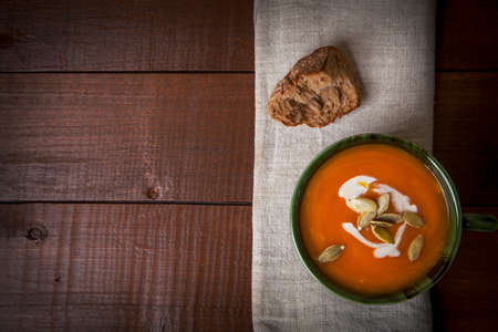 Pumpkin soup in bowl with cream and seeds on wooden, rustic food stileの写真素材