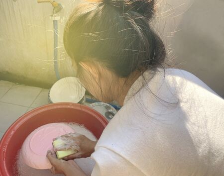 Women washing dishes. washes the frying pan with a detergent and sponge.