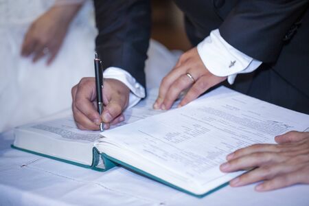 groom signs wedding deed in marriage handsの写真素材