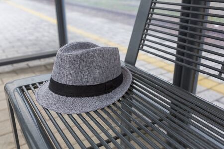 gray hat on metal bench at the train stop