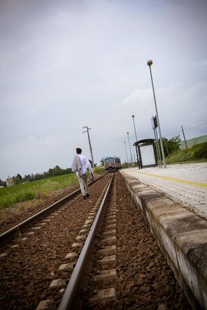 man with suitcase along train tracks failing job loss