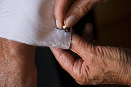 mother of the groom fastening cuffs and cufflinks before the wedding