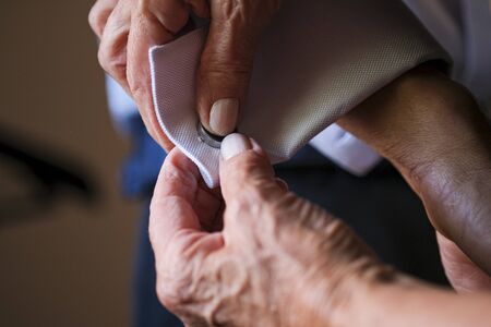 mother of the groom fastening cuffs and cufflinks before the wedding