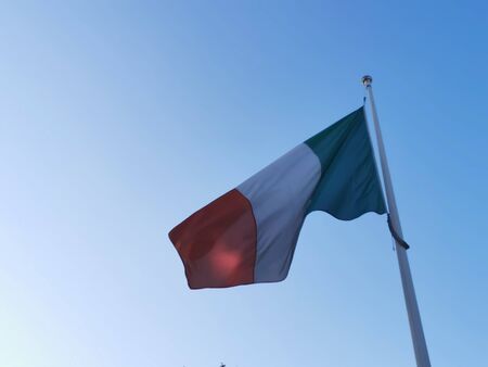 Italian flag waving on flagpole on sunny dayの写真素材