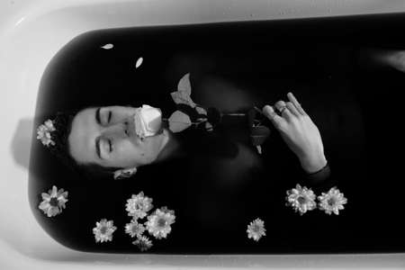 beautiful boy with white shirt posing in bathtub portrait while smokingの写真素材