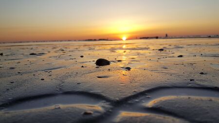 sunrise on the beach of the mediterranean sea in riccione rimini with sun reflected sand and wavesの写真素材