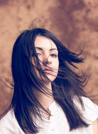 portrait of beautiful dark-haired girl with long hair blowing in the wind. High quality pportrait of beautiful dark-haired girl with long hair blowing in the windhotoの写真素材