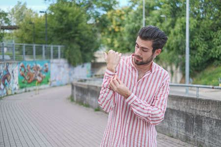 beautiful dark-haired boy in the city center with short pants and striped shirt. High quality photo