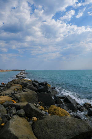 rocks with splashes of sea waves and blue sky ostia rome. High quality photo