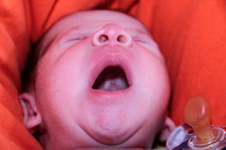 newborn baby yawning on sofa with open mouth. High quality photoの写真素材