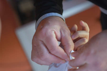 father fastens the cuffs of the boy's shirt at the first communion. High quality photo