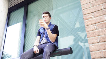 handsome Boy in jeans jacket uses smartphone, High quality photo