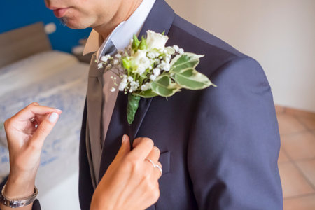 sister places a small bouquet in the groom's pocket. High quality photoの写真素材