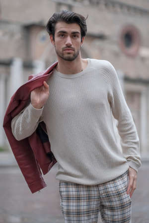 beautiful guy with red leather jacket and backpack in the center of reggio emilia. High quality...