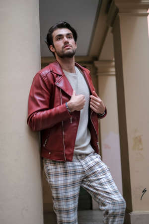 beautiful guy with red leather jacket and backpack in the center of reggio emilia. High quality photoの写真素材