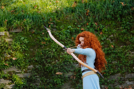Lucca, Italy - 2018 10 31: Lucca Comics free cosplay event around city The Brave Merida with bow. High quality photoのeditorial素材