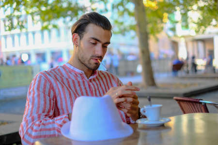 beautiful dark-haired italian guy smokes at the bar. High quality photoの写真素材