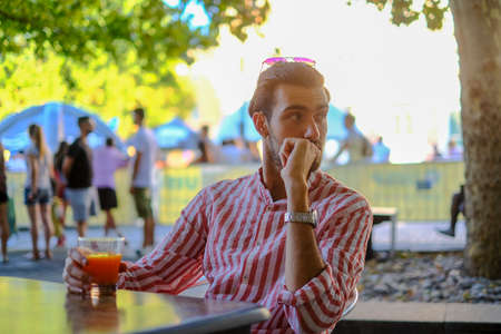 beautiful dark-haired Italian guy drinks a fruit juice at the bar. High quality photoの写真素材