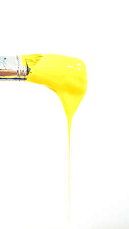paintbrush with dripping yellow paint on white background. High quality photo