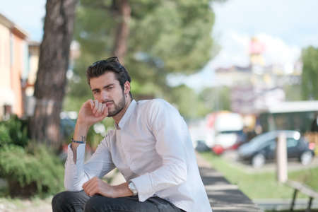 beautiful Italian dark-haired boy sitting under the trees thoughtfully. High quality photoの写真素材