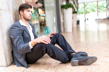 beautiful Italian dark-haired boy sitting on the ground in the city center. High quality photoの写真素材