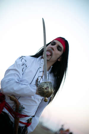 long-haired boy with vampire pirate costume and sword. High quality photo