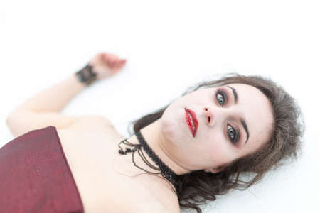 beautiful brunette vampire girl with blood red dress lying dead in the snow. High quality photo
