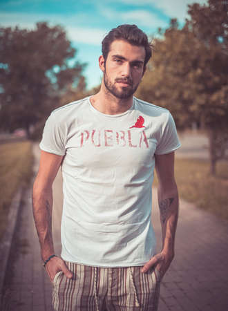 handsome Italian dark-haired guy with t-shirt is walking. High quality photo