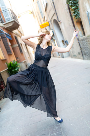 beautiful Italian brunette girl dances in the center of Reggio Emilia in the alleys with long skirt. High quality photoの写真素材