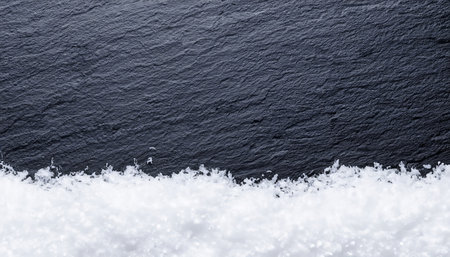 snow on a black stone background with a place for your textの素材