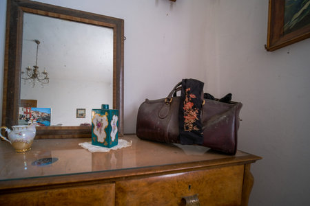 There is a dresser with a mirror and a bag placed on top of it in the room. The furniture adds to...