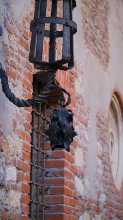 A decorative wrought iron lantern hangs elegantly on the surface of a brick wall, adding charm and style to the architectural compositionの写真素材