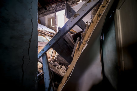 In a room that features a staircase in disrepair as well as a wall that is also broken, the...