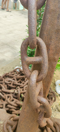 The image presents a closeup view of a rusty chain lying upon a rough concrete surface, showing its weathered texture and historyの写真素材