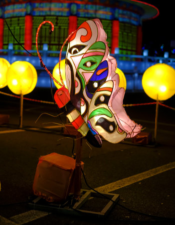 At night, a lantern featuring a vibrant face design is illuminated, casting an orange hue that adds a whimsical touch to the darknessの写真素材