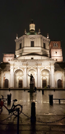 A large and impressive building is beautifully lit up at night, with a bicycle parked right in front of it, adding to the sceneの写真素材