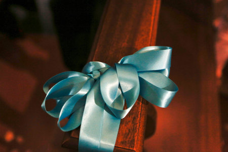 A beautiful blue ribbon is expertly tied to a sturdy wooden railing, making it an eyecatching decoration for any event or occasionの写真素材