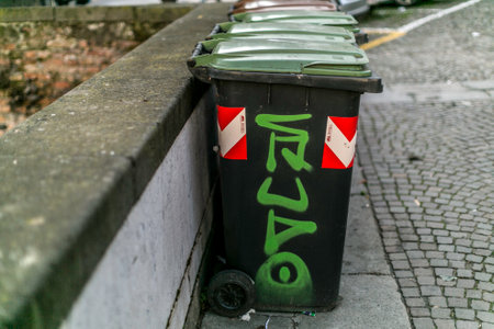 A black trash can featuring vibrant green graffiti on its surface that boldly says a word, making it stand outの写真素材